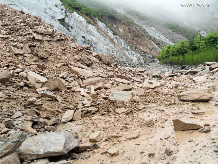 Traffic police are on duty at the landslide-hit highway linking Wenxian County and Bikou Township in northwest China's Gansu Province, July 9, 2013. Rainstorms battered the region these days. (Xinhua)