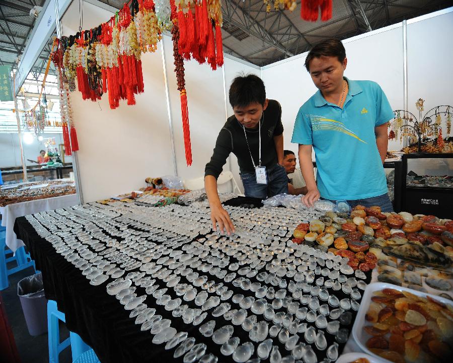 An exhibitor lays out jade pendants at the 2013 China Pan-Asia Stone Expo in Kunming, capital of southwest China's Yunnan Province, July 10, 2013. The eight-day expo kicked off Wednesday at the Kunming International Convention and Exhibition Center. (Xinhua/Qin Lang)