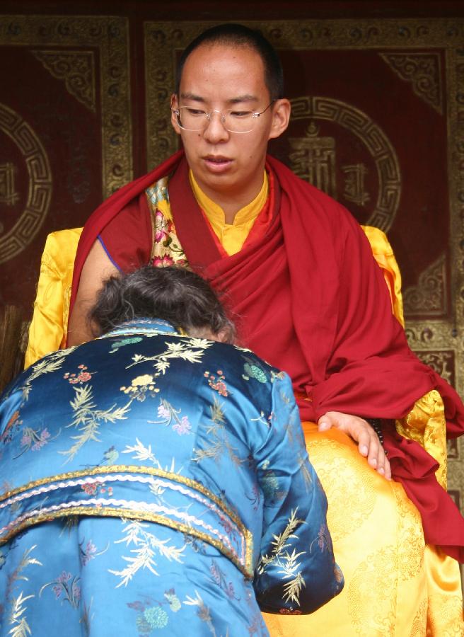 The 11th Panchen Lama Bainqen Erdini Qoigyijabu gives blessing to a devotee at the Taer Monastery in Huangzhong County, northwest China's Qinghai Province, July 2, 2013. The Panchen Lama visited Qinghai and held Buddhist ceremonies there from June 30 to July 9. (Xinhua/Gu Ling)