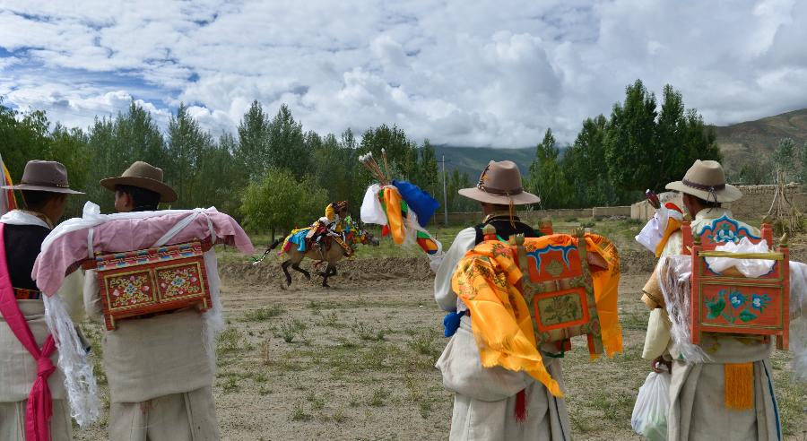 Farmers in holiday array watch performance during an Ongkor Festival prayer ceremony in Gonggar County, southwest China's Tibet Autonomous Region, July 10, 2013. Farmers of the Tibetan ethnic group pray for good harvests during the annual Ongkor Festival, or Bumper Harvest Festival. In doing so, the farmers walk around crop fields in praying processions led by Buddhist lamas and elder members of the community. (Xinhua/Purbu Zhaxi)