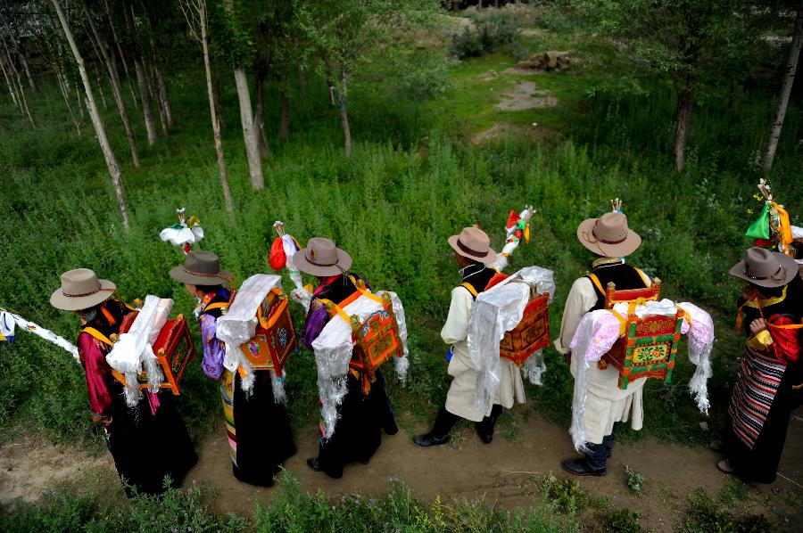 Farmers in holiday array attend an Ongkor Festival prayer ceremony in Gonggar County, southwest China's Tibet Autonomous Region, July 10, 2013. Farmers of the Tibetan ethnic group pray for good harvests during the annual Ongkor Festival, or Bumper Harvest Festival. In doing so, the farmers walk around crop fields in praying processions led by Buddhist lamas and elder members of the community. (Xinhua/Purbu Zhaxi)