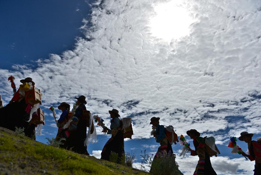 Farmers in holiday array attend an Ongkor Festival prayer ceremony in Gonggar County, southwest China's Tibet Autonomous Region, July 10, 2013. Farmers of the Tibetan ethnic group pray for good harvests during the annual Ongkor Festival, or Bumper Harvest Festival. In doing so, the farmers walk around crop fields in praying processions led by Buddhist lamas and elder members of the community. (Xinhua/Purbu Zhaxi)
