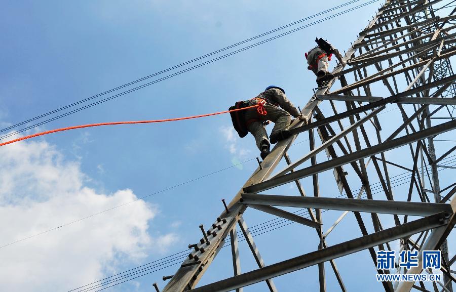 Two workers with Transmission and Distribution Engineering Company of Fujian Province climb up the 50-meter-tall No. 42 electric tower to check the equipment in Xiamen, southeast China's Fujian province, July 4, 2013. (Photo/Xinhua)