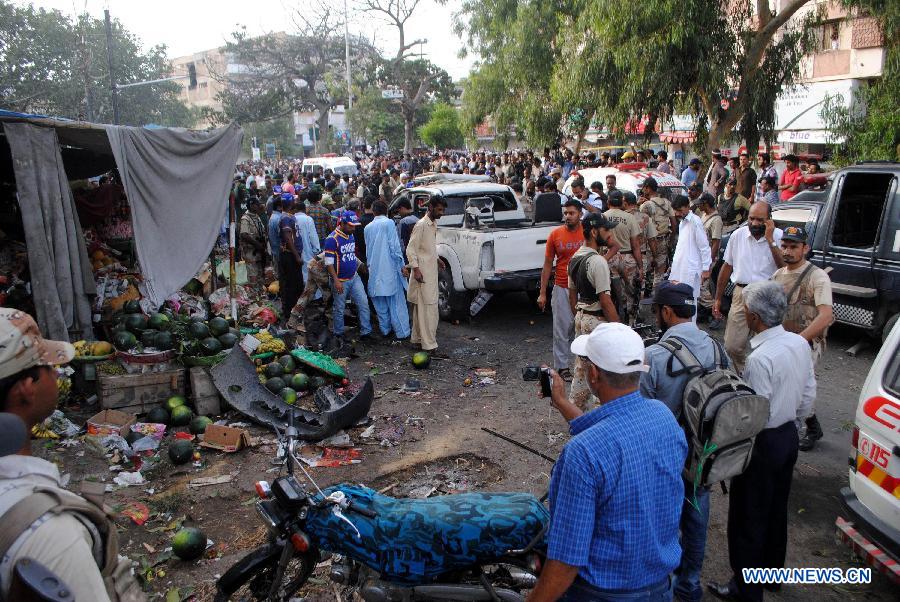 Security officials and other people gather at the suicide blast site in southern Pakistani port city of Karachi on July 10, 2013. Pakistani President Asif Ali Zardari's chief security officer Bilal Ahmad Sheikh was killed in a suicide bomb blast in southern port city of Karachi on Wednesday, police said. (Xinhua/Arshad)