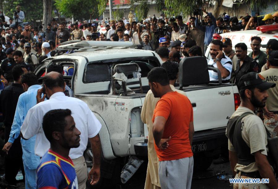 Security officials gather around a destroyed vehicle at the suicide blast site in southern Pakistani port city of Karachi on July 10, 2013. Pakistani President Asif Ali Zardari's chief security officer Bilal Ahmad Sheikh was killed in a suicide bomb blast in southern port city of Karachi on Wednesday, police said. (Xinhua/Arshad)