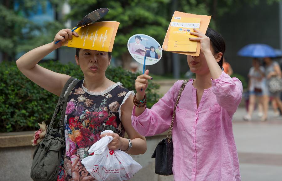 Two women walk on Guangyinqiao walking street during a heat wave in Chongqing, southwest China's municipality, July 11, 2013. Local meteorological observatory issued an orange-coded alert of heat on Thursday, as temperature in some parts of Chongqing has risen up to 37 degrees Celsius. (Xinhua/Chen Cheng)