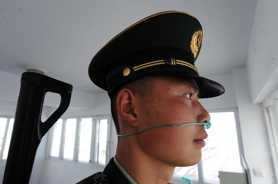 Armed policeman Wu Fengfan takes in oxygen while guarding the Qinghai-Tibet Railway in northwest China's Qinghai Province, July 9, 2013. The armed policemen overcome the harsh climate and lack of oxygen, and stick to their post. (Xinhua/Hou Deqiang)