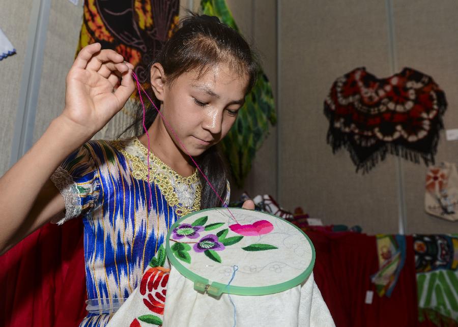 A girl embroiders in an exhibition held in Urumqi, capital of northwest China's Xinjiang Uygur Autonomous Region, July 12, 2013. The first session of Xinjiang Presents Design Competition that kicked off from April has received more than 900 pieces of artworks including sculptures, paintings, embroidery, paper cutting and pottery. (Xinhua/Wang Fei) 