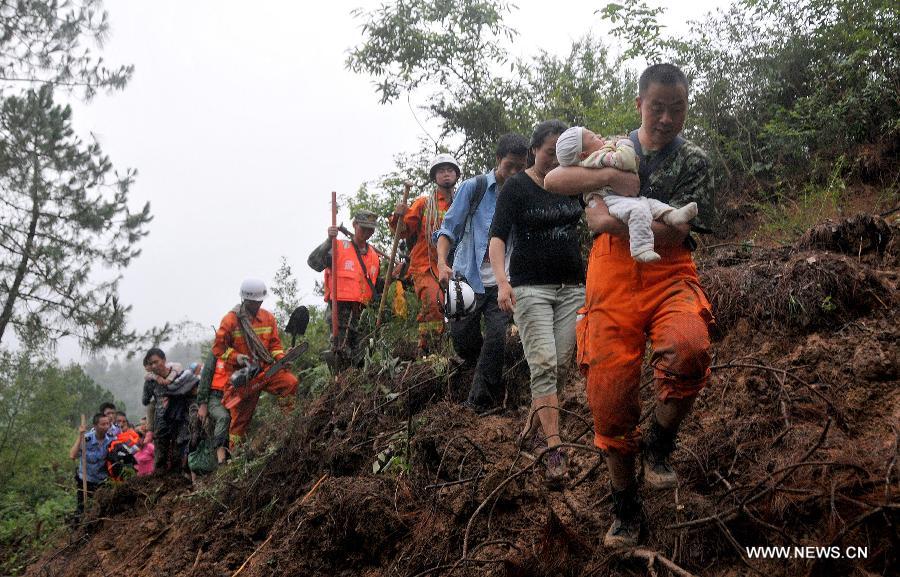 Rescuers help transfer villagers to a safety place in Hongxi Village of Pingwu County in Mianyang City, southwest China's Sichuan Province, July 12, 2013. Four people were injured and one was missing in a rain-triggered mudslide on Friday. Most of the houses in the village were buried in the mud. (Xinhua/Hu Yu) 