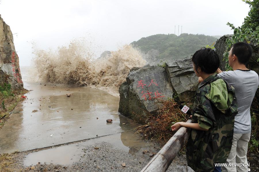Journalists shoot the big waves brought by the strong wind along a sea dike in Cangnan County, east China's Zhejiang Province, July 13, 2013. Typhoon Soulik is expected to make a landfall in Fujian and Zhejiang provinces on the Chinese mainland between Saturday noon and late afternoon after it passes Taiwan. (Xinhua/Ju Huanzong) 