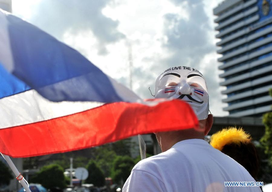 A protester wearing a mask holds up a national flag during a rally in front of Lumpini Park in Bangkok, capital of Thailand, July 14, 2013. A number of anti-government protesters rallied in Bangkok and other ten more provinces in Thailand. (Xinhua/Gao Jianjun)