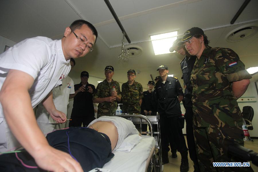 Soldiers from Netherlands' Van Speijk vessel observe acupuncture treatment on Chinese People's Liberation Army Navy hospital ship "Peace Ark" in Gulf od Aden, July 14, 2013. It was the first time PLA Navy hospital ship "Peace Ark" provided medical treatment for foreign soldiers during its 10-day mission to Gulf of Aden. (Xinhua/Ju Zhenhua) 