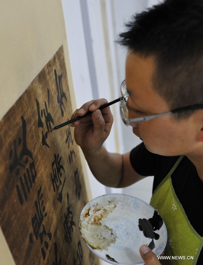 Yang Liguang, a technicist on cultural relics preservation, repairs an ancient calligraphy work at the relics conservation center of the museum of Tianshui City, northwest China's Gansu Province, July 15, 2013. A total of six cultural relics preservation experts of the museum conduct the conservation work on relic items here. They use modern technology as well as traditional handicraft to repair and restore cultural relic fragments and damaged bronze wares. (Xinhua/Chen Bin) 