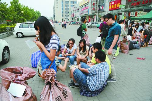 Several students play cards on the floor while waiting.（Photo/China Youth Daily）