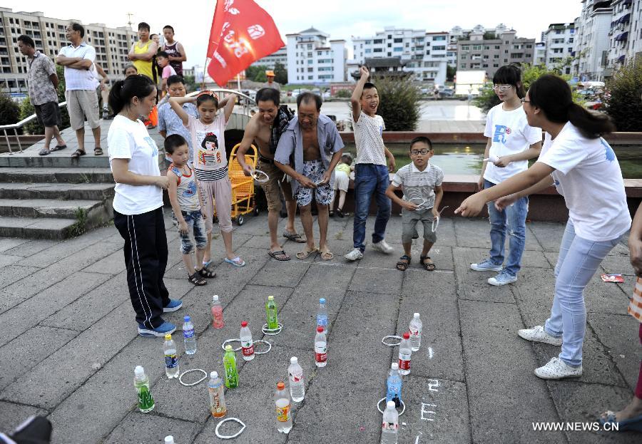 Photo taken on July 15, 2013 shows residents playing ringtoss game at Hongmen Square in Dongyang City, east China's Zhejiang Province. Many residents participated in the activity of old games organized by students from Zhejiang Normal University on Monday. (Xinhua/Bao Kangxuan) 