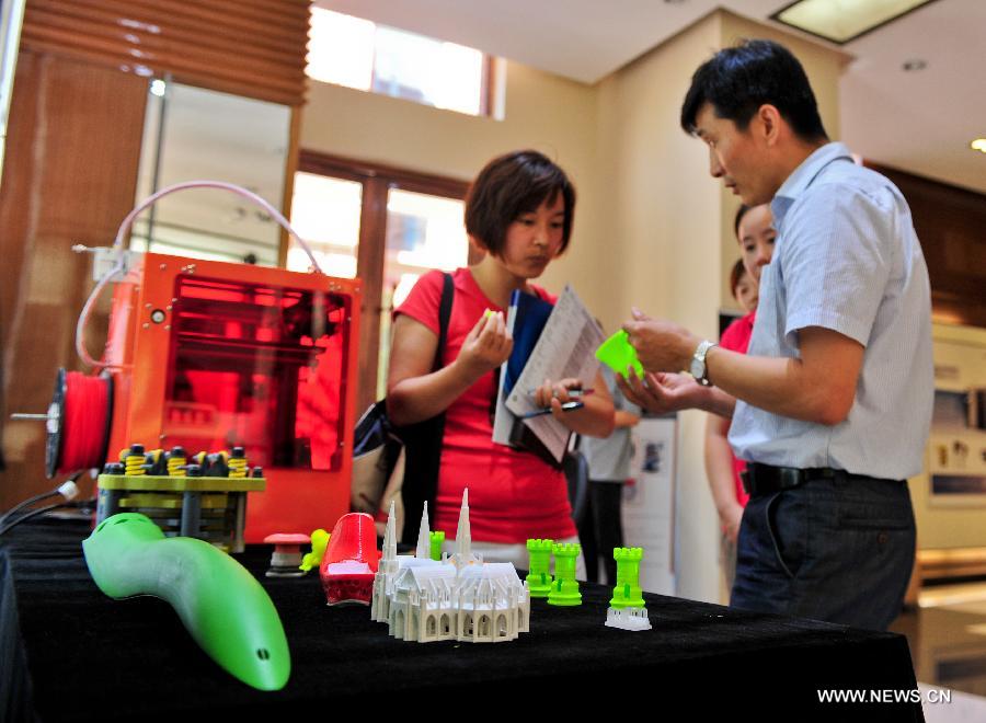 A staff member (R) receives customers at a 3D-printing experience store in Tianjin, north China, July 16, 2013. (Xinhua/Zhai Jianlan)  