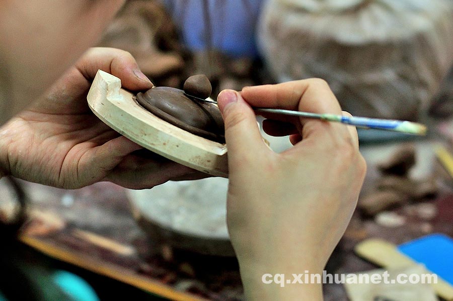 A craftsman makes a teapot lid in a workshop in Anfu Town, Rongchang County, Chongqing, July 13, 2013. (Xinhua/Li Xiangbo)