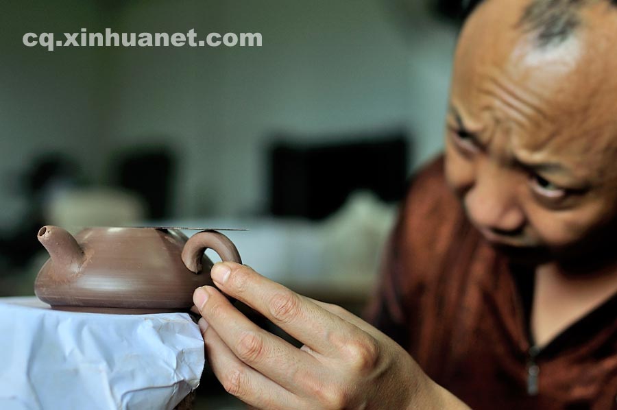 A craftsman makes a handle for a teapot in a workshop in Anfu Town, Rongchang County, Chongqing, July 13, 2013. (Xinhua/Li Xiangbo)