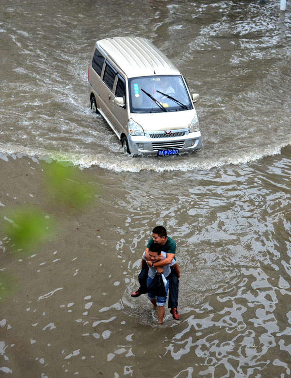 A young man carries his friend wading in a flooded street in central China’s Wuhan city, July 7, 2013. The city was hit by the strongest rainstorm in five years and a number of vehicles and people had to travel in the water. (Xinhua/Cheng Min) 