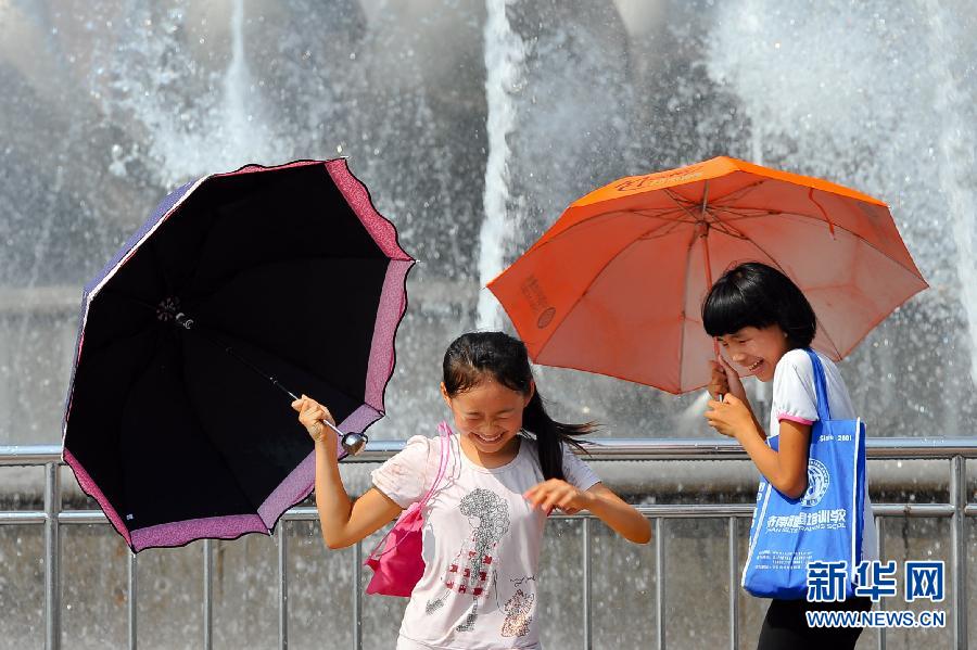 Two children play water beside the musical fountain on the Quancheng Square in Jinan, capital of east China's Shandong province on July 3, 2013. The temperature in Jinan reached 38 degrees Celsius that day. (Xinhua/Guo Xulei)