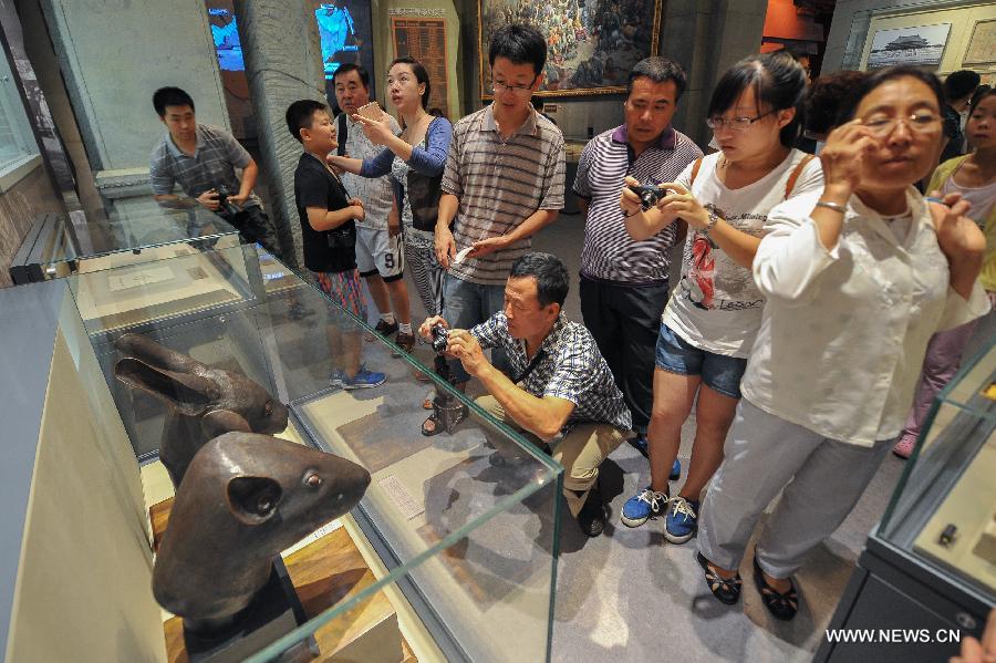 Visitors view the bronze heads of a rat and a rabbit, donated by the Pinault family of France in April, at the National Museum of China in Beijing, capital of China, July 18, 2013. The two pieces of relics were among 12 animal head sculptures that formed a zodiac water clock previously stood at Yuanmingyuan, or the Old Summer Palace, in northwest Beijing. They were looted by Anglo-French Allied forces during the Second Opium War in 1860. (Xinhua/Zhao Dingzhe)