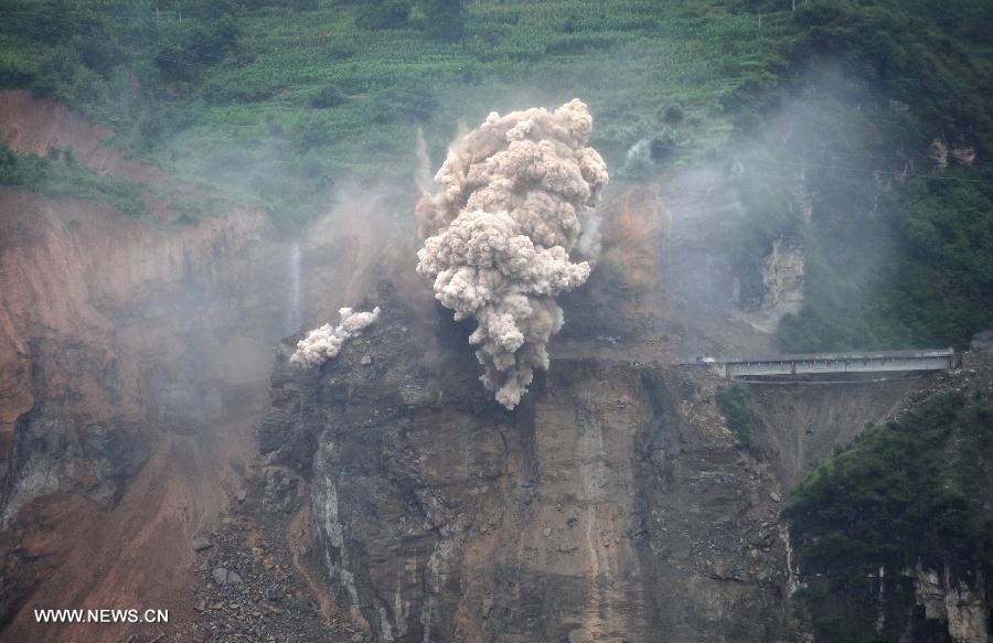 Photo taken on July 18, 2013 shows the blasting site above a barrier lake in Sanjiao Township of Hanyuan County, southwest China's Sichuan Province. The blasting is conducted to remove dangerous rocks and then dig channels to discharge the floodwater of the barrier lake. The lake was formed after a landslide and continuous rainfall, threatening residents downstream in Sichuan. (Xinhua/Xue Yubin)