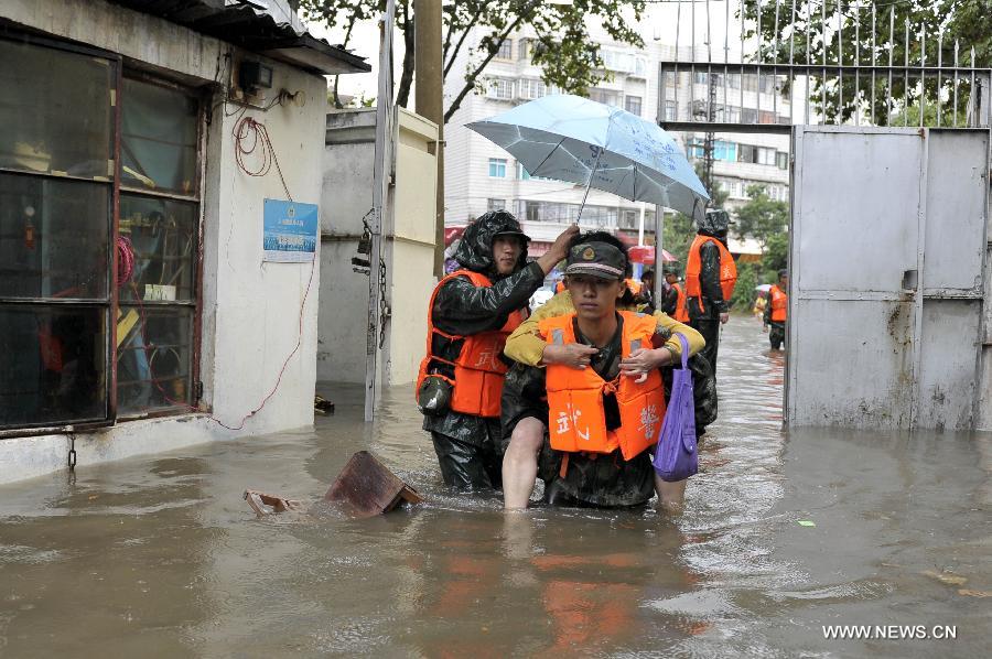 A rescuer carrying an elder citizen walks on the flooded Chuanjin Road in Kunming, capital of southwest China's Yunnan Province, July 19, 2013. Kunming was hit by a heavy rainstorm from Thursday to Friday. Kunming's meteorologic center on Friday issued a blue alert for rainstorm. (Xinhua/Hao Yaxin)