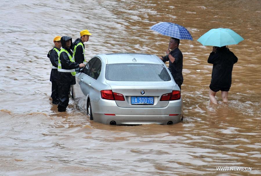 Rescuers help a citizen push the car on the flooded Jinbi Road in Kunming, capital of southwest China's Yunnan Province, July 19, 2013. Kunming was hit by a heavy rainstorm from Thursday to Friday. Kunming's meteorologic center on Friday issued a blue alert for rainstorm. (Xinhua/Lin Yiguang)