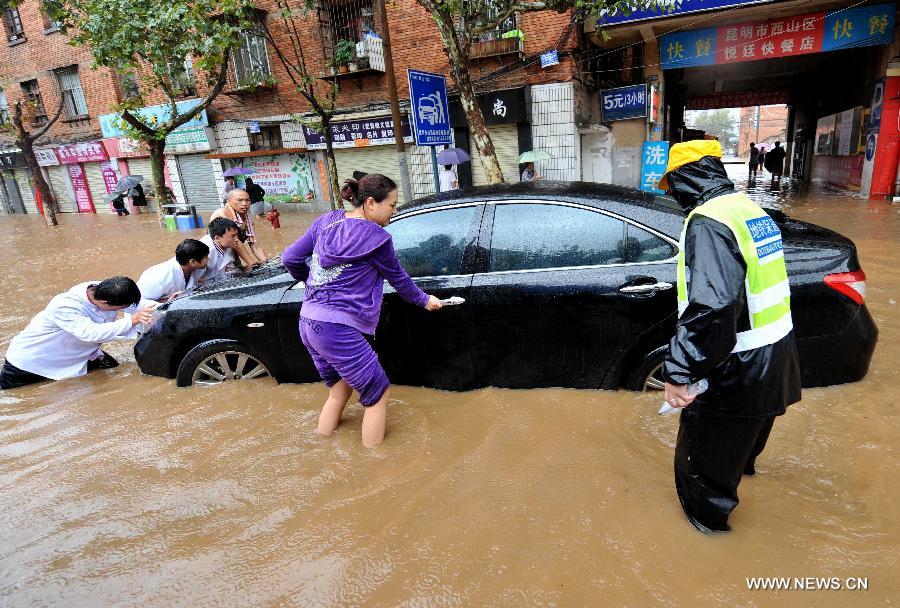 People push a submerged car in the flood water in Kunming, capital of southwest China's Yunnan Province, July 19, 2013. Kunming was hit by a heavy rainstorm from Thursday to Friday. (Xinhua/Lin Yiguang)