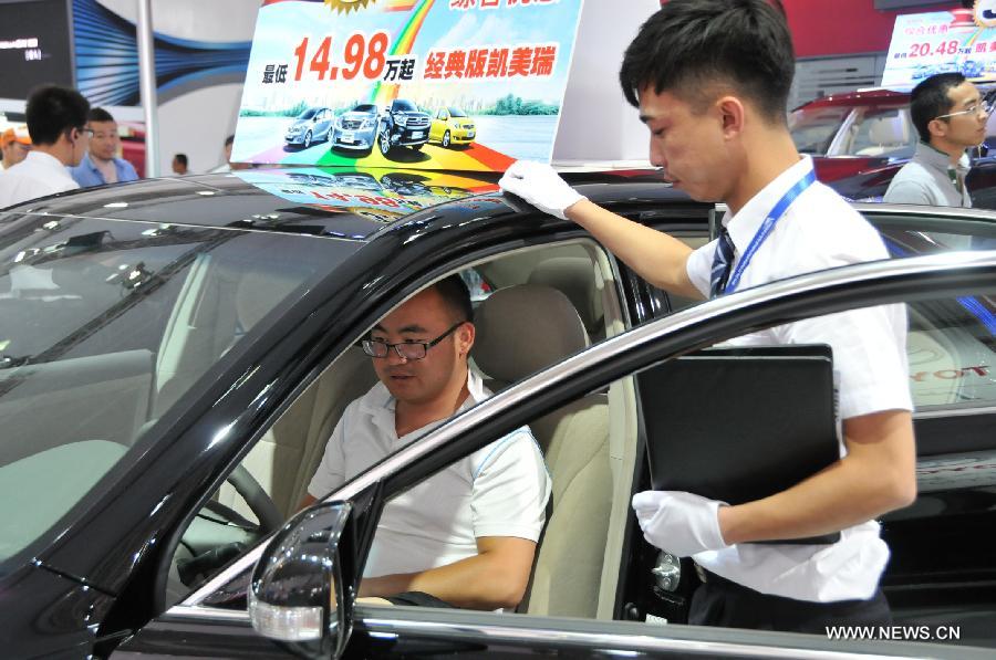 A staff member (R) introduces a vehicle to a visitor at the 5th Huhhot International Auto Exhibition in Huhhot, north China's Inner Mongolia Autonomous Region, July 19, 2013. Some 400 vehicles from more than 70 enterprises and brands were taken to the five-day exhibition which kicked off on Friday. (Xinhua/Liu Yide)