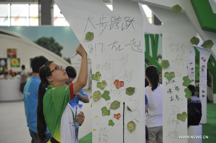 A volunteer writes her environmental statements onto an artificial tree during the first China Ecological Products (Technologies) Expo in Guiyang, capital of southwest China's Guizhou Province, July 19, 2013. The five-day expo, a key part of the 2013 Eco-Forum Global Annual Conference, kicked off here Friday. More than 260 exhibitors will attend the expo to introduce their advanced concepts and techniques in the filed of ecology. (Xinhua/Ou Dongqu)