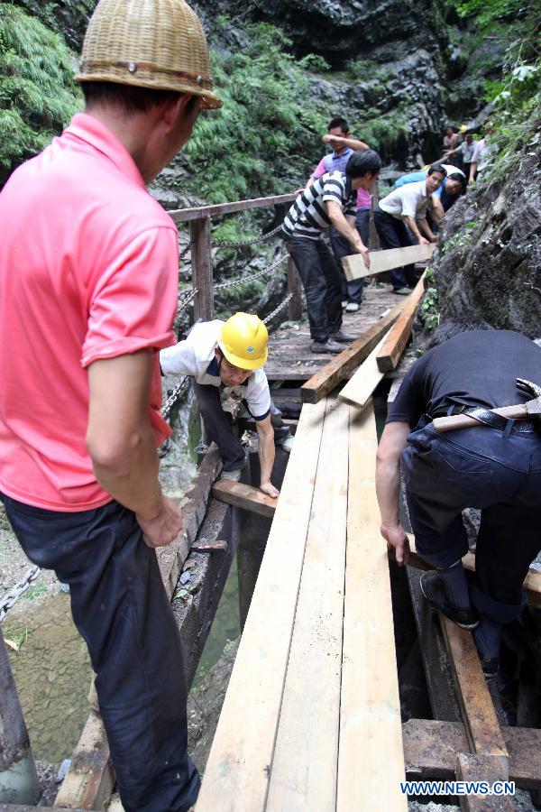 Workers repair a rim skywalk after a landslide in the Jinsixia Gorge, northwest China's Shaanxi Province, July 21, 2013. One tourist was killed and 18 others injured by falling rocks at Jinsixia Gorge on Sunday morning. The gorge has been closed temporarily. (Xinhua)