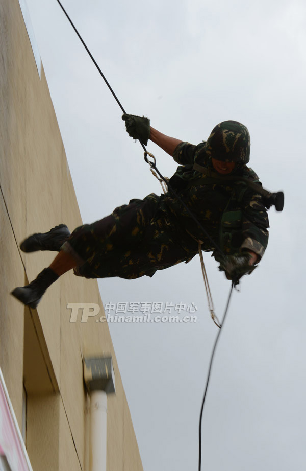 The special operation members use a rope to climb a 12-meter-high building, and then slide down from the building on the another side. (China Military Online/Li Jing)