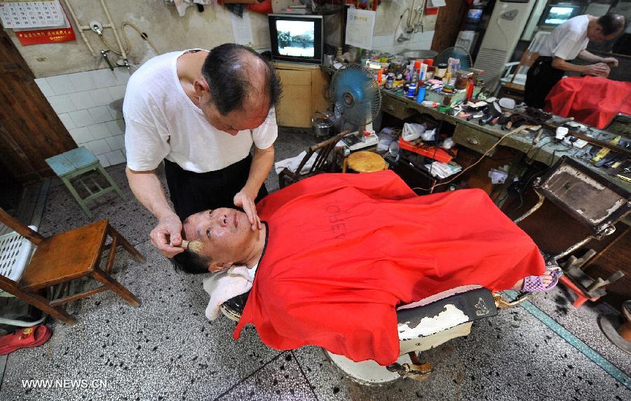 Ou Shubin serves a customer at his old-fashioned barbershop at No. 76, Meihua Road in Ningxiang County, central China's Hunan Province, July 21, 2013. Affectionately known as Ou Die, or Daddy Ou in the neighborhood, the 78-year-old barber has been in the business for 66 years and run the current shop for 33 years, offering traditional services to old customers. (Xinhua/Long Hongtao) 