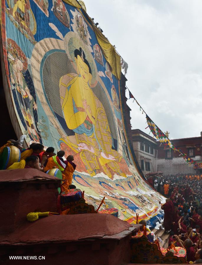 Devotees worship a huge Buddha portrait after unfolding it during the annual religious ritual in the Gandan Temple in Lhasa, capital of southwest China's Tibet Autonomous Region, July 22, 2013. Founded in 1409 by followers of Zong Kaba, founder of the Yellow Sect of Tibetan Buddhism, the Gandan Temple is the oldest among lamaseries of the Yellow Sect. (Xinhua/Purbu Zhaxi)