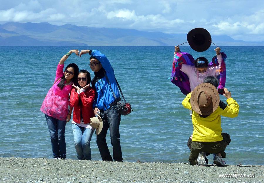 Tourists pose for photos beside Lake Namtso in southwest China's Tibet Autonomous Region, July 19, 2013. Namtso, meaning "the heavenly lake" in Tibetan language, has become one of the preferences for a growing number of tourists to Tibet. (Xinhua/Wang Song)