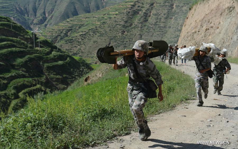 Rescuers carry relief supplies to Yongguang Village of Meichuan Town in Minxian County, northwest China's Gansu Province, July 22, 2013. The death toll has climbed to 89 in the 6.6-magnitude earthquake which jolted a juncture region of Minxian County and Zhangxian County in Dingxi City Monday morning. (Xinhua/Zhang Yongjin) 