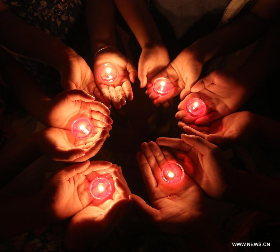 Volunteers hold candles as they pray for the residents and victims of quake-hit Dingxi City in northwest China's Gansu Province, in Loudi City, central China's Hunan Province, July 22, 2013. A 6.6-magnitude earthquake jolted a juncture region of Minxian County and Zhangxian County in Dingxi City Monday morning, leaving 89 people dead. (Xinhua/Guo Guoquan)