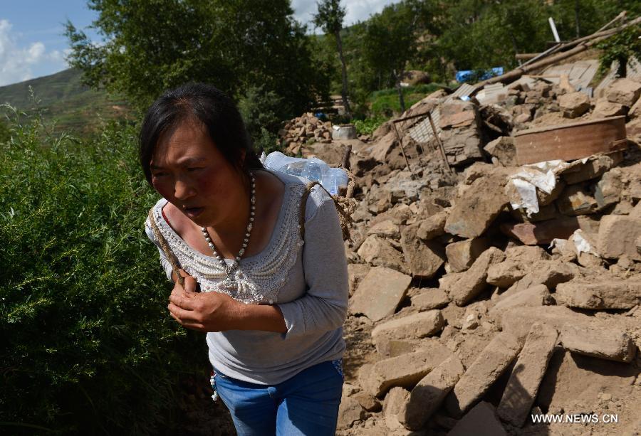 A villager carries food at quake-hit Yongxing Village of Minxian County, northwest China's Gansu Province, July 23, 2013. The death toll has climbed to 94 in the 6.6-magnitude earthquake which jolted a juncture region of Minxian County and Zhangxian County in Dingxi City Monday morning. (Xinhua/Liu Xiao)