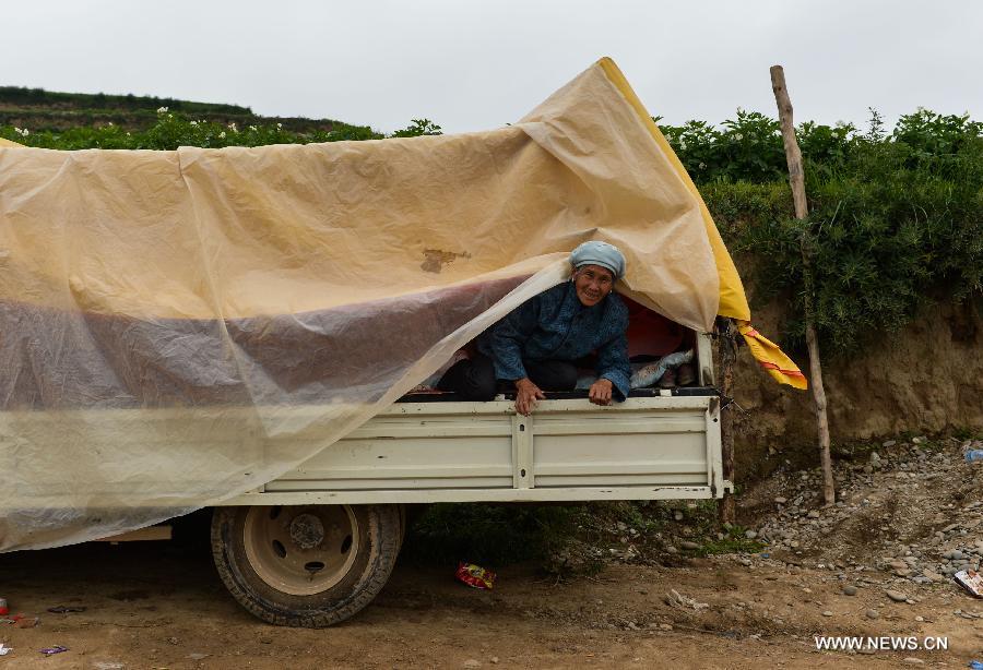 A villager rests on a truck at quick-hit Yongguang Village of Minxian County, northwest China's Gansu Province, July 23, 2013. The death toll has climbed to 94 in the 6.6-magnitude earthquake which jolted a juncture region of Minxian County and Zhangxian County in Dingxi City Monday morning. (Xinhua/Liu Xiao)