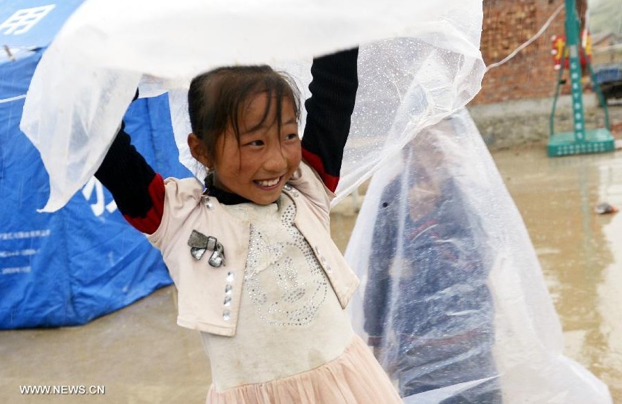 A little girl plays in rain at a temporary settlement for quake-affected people in Qingtu Village of Minxian County, northwest China's Gansu Province, July 24, 2013. A rainfall hit the quake-jolted region in Gansu on Wednesday. The death toll has climbed to 95 in the 6.6-magnitude earthquake which jolted a juncture region of Minxian County and Zhangxian County in Dingxi City Monday morning. (Xinhua/Liu Xiao)