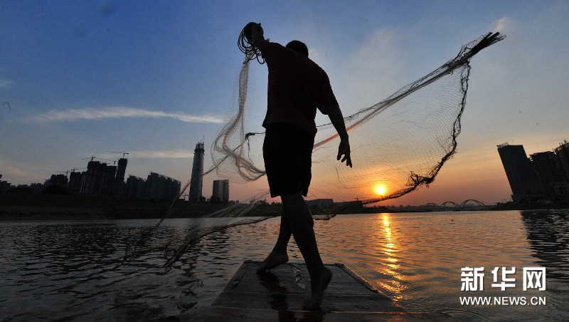 Yi Guojun sets the boat in deep water area and throws the net in early evening. (Photo by Long Hongtao/ Xinhua)
