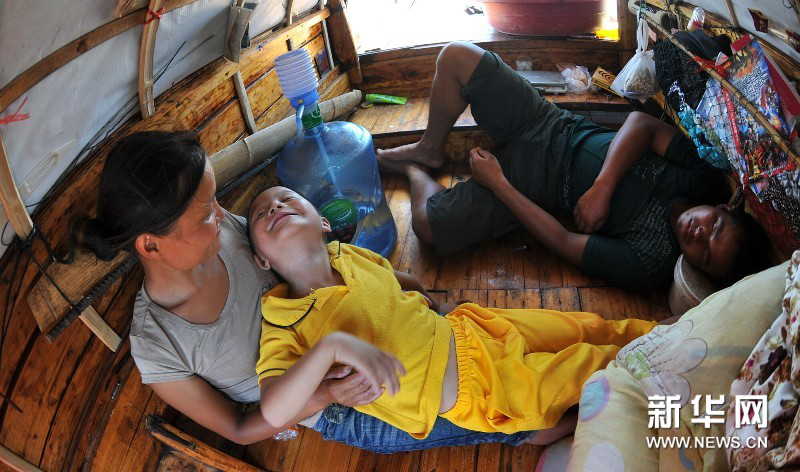 Yi Guojun falls asleep at noon. His wife Chen Yan chats with their son aboard the boat. (Photo by Long Hongtao/ Xinhua)