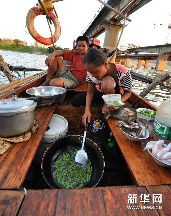 Yi Guojun watches his wife cooking at the stern. (Photo by Long Hongtao/ Xinhua)
