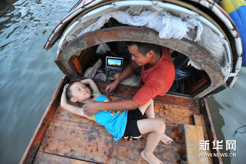 Yi Guojun and his son play games aboard the boat. (Photo by Long Hongtao/ Xinhua)