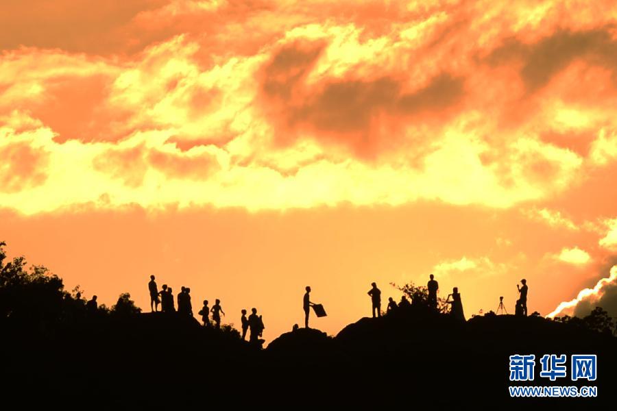 July 23, visitors watch the sunset glow on the peak of Baoshi Mountain to the north of the West Lake. According to Hanzhou meteorological observatory, the highest temperature reached 39.6 degrees Celsius. (Photo/Xinhua)