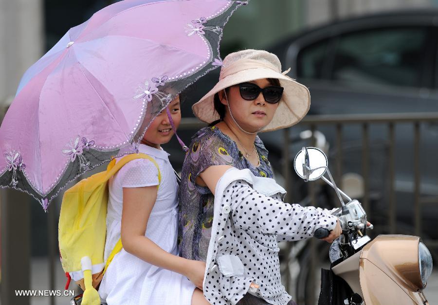 Citizens shield themselves from the heating sun in Hangzhou, capital of east China's Zhejiang Province, July 26, 2013. A lingering hot wave hit the city, with the highest temperature reaching above 40 degrees Celsius in these three days. (Xinhua/Ju Huanzong)