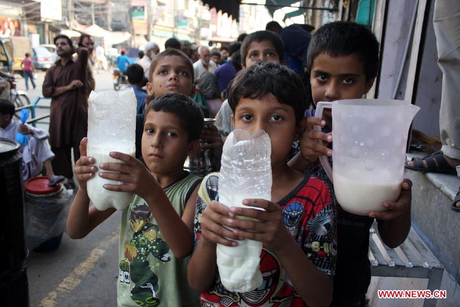 Poor Pakistani children show milk at free milk distribution counter during the holy month of Ramadan in eastern Pakistan's Lahore on July 26, 2013. Muslims around the world refrain from eating, drinking and smoking from dawn to dusk during the fasting month of Ramadan. (Xinhua/Jamil Ahmed)