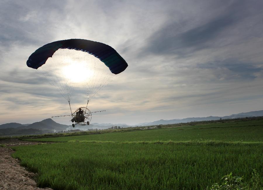 A paramotor sprays pesticide at the Hongguang Farm in Duchang County, east China's Jiangxi Province, July 26, 2013. Paramotors are used to spray pesticide in the air in Duchang County, since it's the critical period to prevent and wipe out paddy rice diseases and insect pests. (Xinhua/Fu Jianbin)