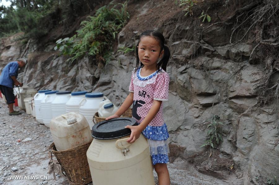 A girl wait for drinking water supply in Longzhao Village, Gaoqiao, Tongxi County, southwest China's Guizhou Province, July 26, 2013. Lingering droughts in Guizhou have affected more than 8.37 million people, local authorities said Friday. Over 1 million people lack adequate supplies of drinking water, and a total of 541,200 hectares of farmland is also affected by the drought, the provincial government said. (Xinhua/Wang Nian)